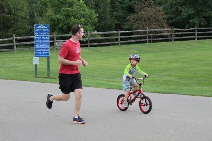 man running alongside child on bike
